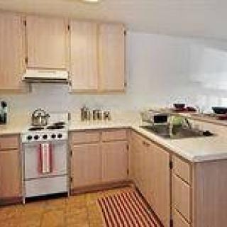 A modern kitchen with wooden cabinets and a small stove.
