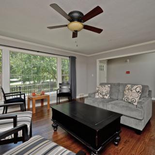 A cozy living room with modern furniture, featuring a large sofa, stylish coffee table, and a ceiling fan.