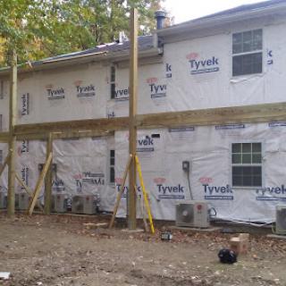 A side view of a house undergoing construction, featuring wooden supports and insulation.