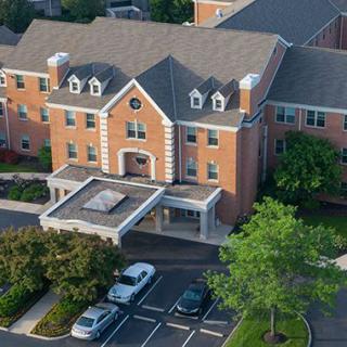 Aerial view of a brick building with a parking lot and surrounding greenery.