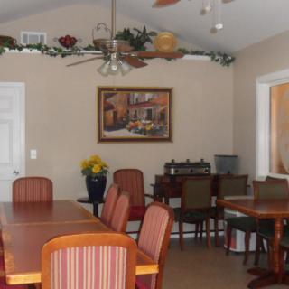 A cozy dining room with a long table surrounded by chairs, adorned with wall decor and plants above.