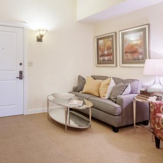 A cozy living room with a sofa, glass coffee table, and decorative artwork on the walls.