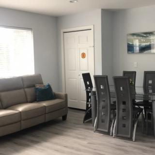A modern living and dining area featuring a beige sofa and a sleek glass dining table with chairs.