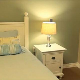 A cozy bedroom with a bedside table and lamp, softly illuminating the serene space.