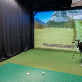 An indoor golf simulator setup with virtual landscape projection.