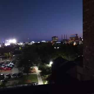 A serene view of the city at night, illuminated by lights and surrounded by nature.