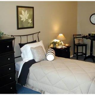 A cozy bedroom with a single bed, a lamp on the nightstand, and wall art.