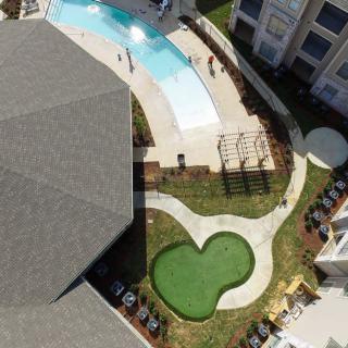 Aerial view of a landscaped outdoor area with a swimming pool and surrounding buildings.