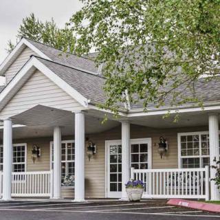 A building with a front porch supported by white columns and surrounded by trees.