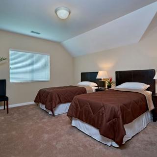 A cozy bedroom with twin beds, a nightstand, and soft lighting.