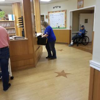 A busy day at an assisted living facility, showcasing staff attending to tasks while residents engage in the environment.