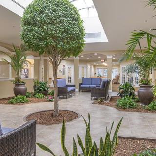 A modern lobby with an indoor garden, featuring lush greenery and comfortable seating under natural light.