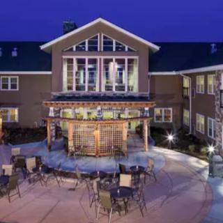 A nighttime view of a building with an illuminated outdoor seating area and patio.