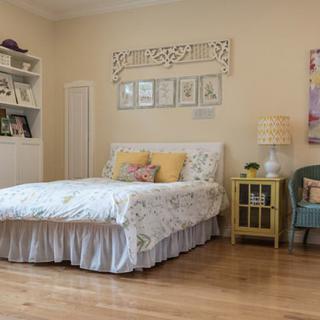 A cozy bedroom with a neatly made bed, bookshelves, and tasteful decor.