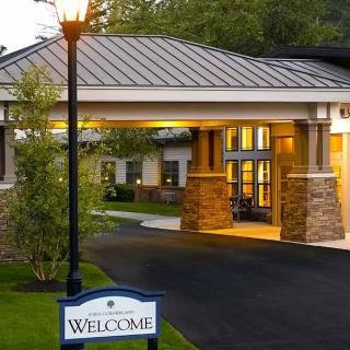 Illuminated entrance to a building with a welcome sign at night.