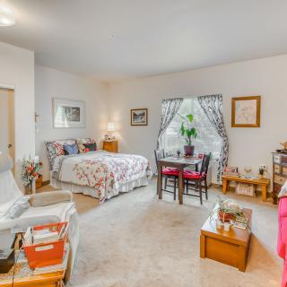 A cozy bedroom with a bed, small dining table, and comfortable seating.