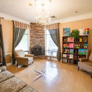 A cozy living room with elegant decor, featuring a fireplace, bookshelf, and comfortable seating.