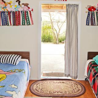 A cozy children's bedroom with twin beds and an open door letting in natural light.