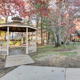 A peaceful park featuring a wooden gazebo surrounded by autumn foliage.