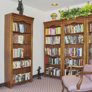 A cozy library corner with wooden bookshelves filled with books and an armchair for reading.
