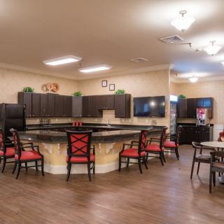 A modern kitchen and dining area featuring a large countertop with barstools and ample lighting.