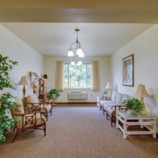 A cozy living room with comfortable seating, plants, and a large window offering natural light.