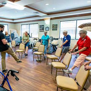 A group of seniors participating in a chair-based exercise class at a community center.
