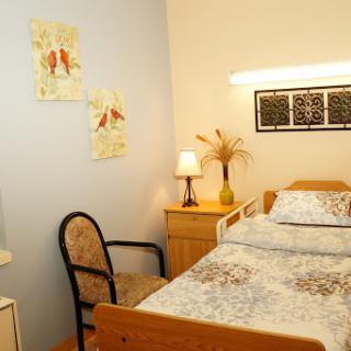 A cozy bedroom featuring a bed with patterned bedding, a chair, and decorative wall art.