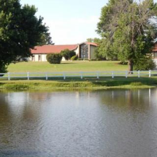 A serene outdoor setting with a pond, house, and surrounding trees.