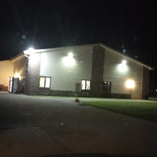 A well-lit building at night with a grassy area in front.