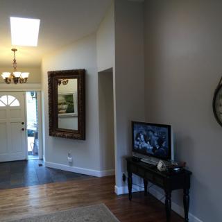 A cozy living space featuring a hallway with a large mirror, a small table with a television, and wood flooring.