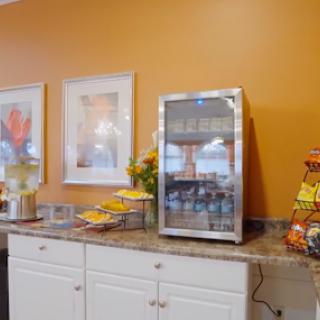 A bright kitchen area featuring an orange wall, a refrigerator, and a selection of breakfast items.