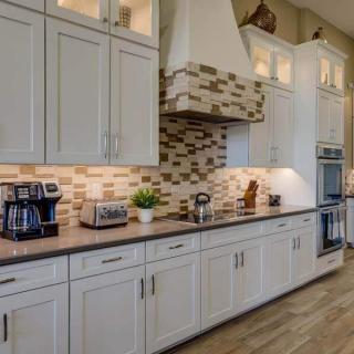 A modern kitchen with white cabinets, a stylish backsplash, and various appliances on the countertop.