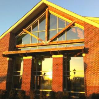 A brick building with large windows reflecting the sunset.