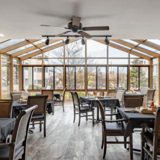 A cozy restaurant dining area with large windows and a ceiling fan.