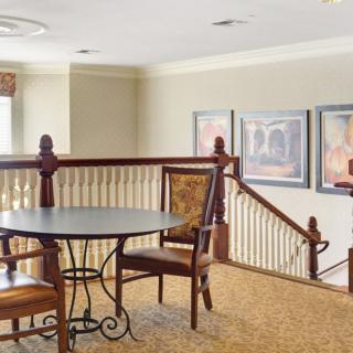 A cozy interior space featuring a small table and chairs near a stair railing, adorned with framed artwork on the walls.