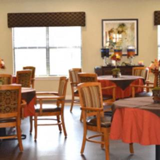 A neatly arranged dining area with tables and chairs, featuring warm decor.