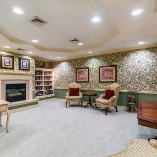 A cozy living room with elegant decor, featuring a fireplace, armchairs, and a bookshelf.