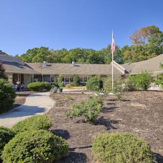 A serene view of a residential building surrounded by well-maintained landscaping and a flagpole.