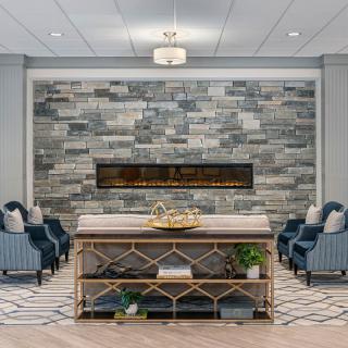 A modern living room with a stone accent wall and built-in fireplace, surrounded by comfortable seating and decorative shelves.