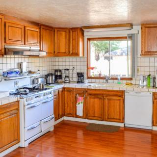 A cozy kitchen featuring wooden cabinets, modern appliances, and a large window over the sink.