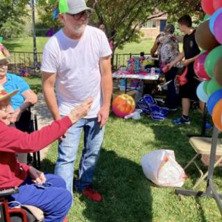 A group of people enjoys a sunny day at an outdoor event with colorful balloons.