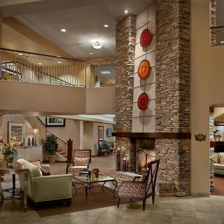 A modern and cozy lobby interior featuring a central fireplace and elegant seating arrangements.