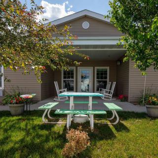 A cozy house with a patio and picnic table surrounded by lush greenery.