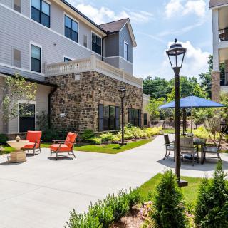 A well-maintained outdoor patio area with seating and an umbrella in a residential apartment complex.