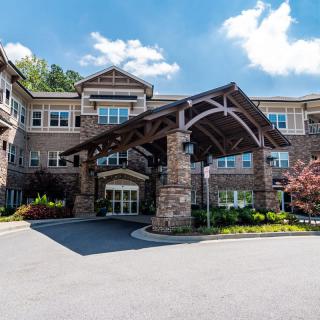 A modern stone-clad residential building with a grand entrance and landscaped surroundings.