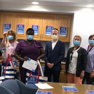 A group of individuals participating in a community support event, all wearing masks and standing together with bags.