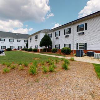 Two-story residential building with a landscaped lawn under a partly cloudy sky.