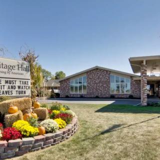 A brick building with a decorative garden and sign in front, under a clear blue sky.