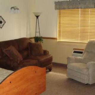 A cozy living room with a sofa, armchair, and lamp by the window.